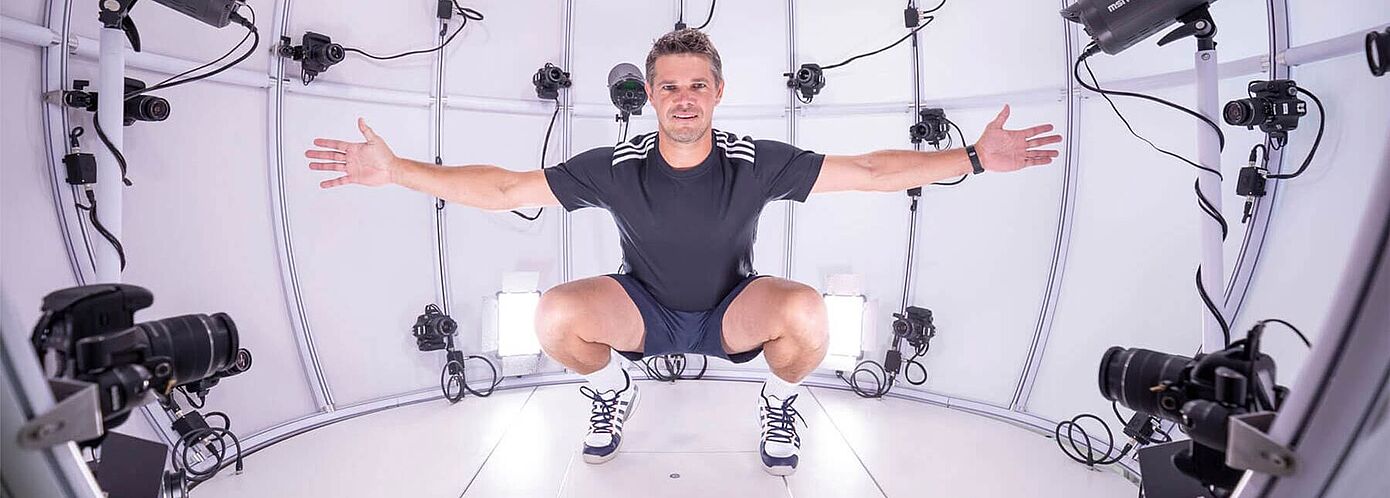 4D Scanning to Measure Fit in Motion at Hohenstein Man squatting in 4D scanner with arms spread wide at Hohenstein